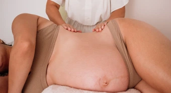 Mujer embarazada recibiendo un masaje relajante en la espalda, resaltando el cuidado y la atención personalizada en un entorno sereno.