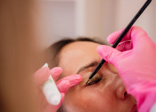 Aplicación de lifting de pestañas con precisión, utilizando herramientas especializadas para realzar la mirada de la cliente.