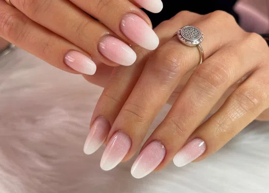 Primer plano de uñas diseñadas con estilo Baby Boomer en tonos rosados y blancos, mostrando un acabado sofisticado y elegante.